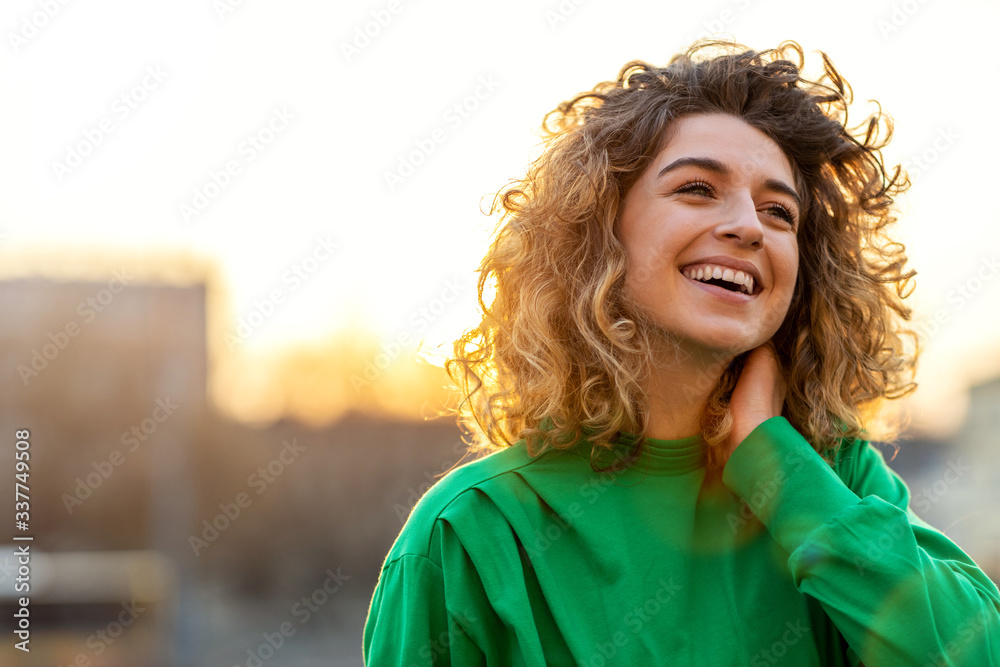Portrait of young woman with curly hair in the city